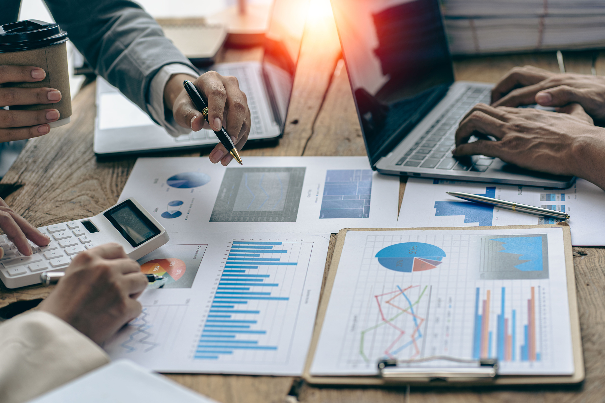 Meet with colleagues to discuss sales analysis in financial reports with graph papers. Financial accounting and business strategy planning related to sales analysis in company marketing reports.